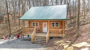 Eine Holzhütte mit einem Metalldach, einer Veranda mit Treppen und einem Kiesgrundstück.