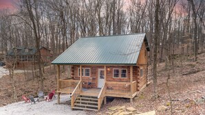 Eine Holzhütte mit Veranda, Kamin und einer Terrasse mit Stühlen.