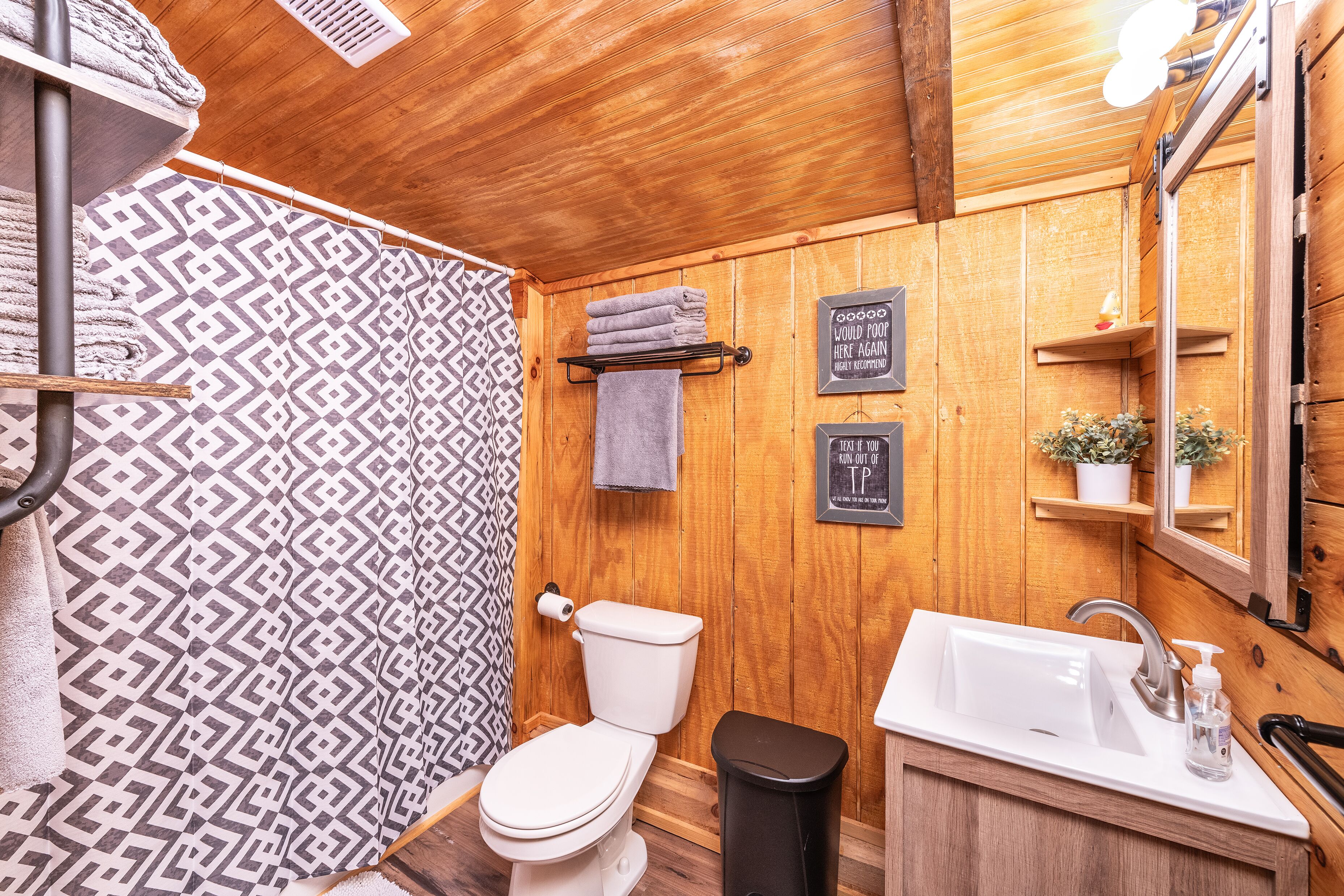 A wooden interior bathroom with a toilet, sink, and shower.
