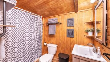 A wooden interior bathroom with a toilet, sink, and shower.