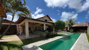 Propiedad residencial con piscina, terraza techada y patio trasero cercado.
