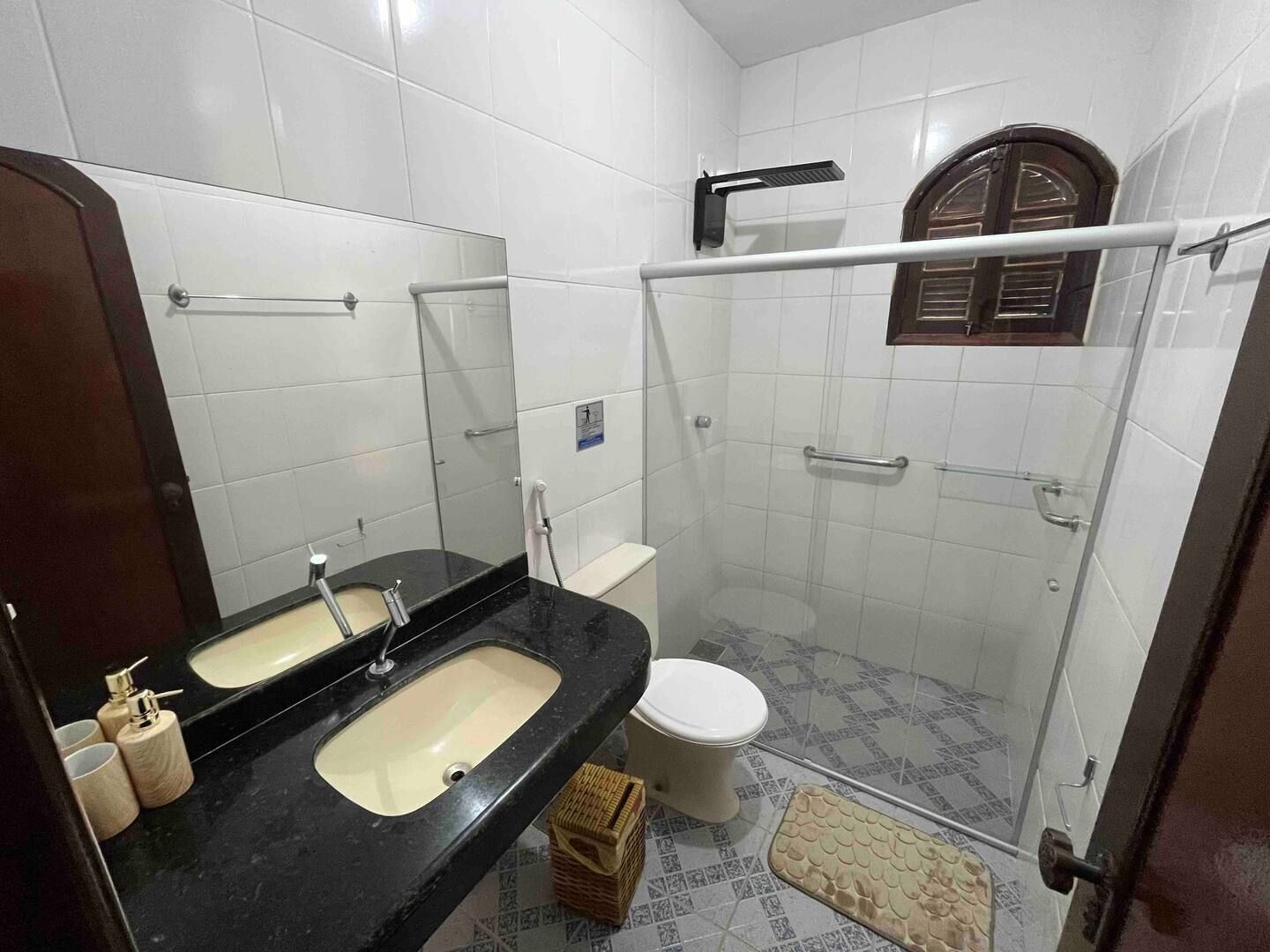 A bathroom with a black sink, white toilet, and a glass-enclosed shower area.