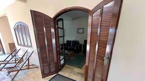 Una puerta con contraventanas de madera, suelo de baldosas y un tapete pequeño.