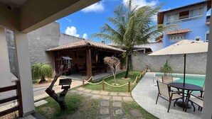 Un patio con piscina, mobiliario exterior y un edificio pequeño.
