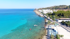 Une ville côtière aux eaux d’un bleu limpide, avec un littoral rocheux et des bâtiments qui bordent la côte.