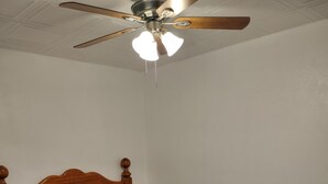 A bedroom with a wooden bed frame, a blue bedspread, a ceiling fan, and a marble floor. - Horse Ranch House 2 miles to Austin,  Remodeled, Relaxed Atmosphere, SXSW Near (Manchaca)