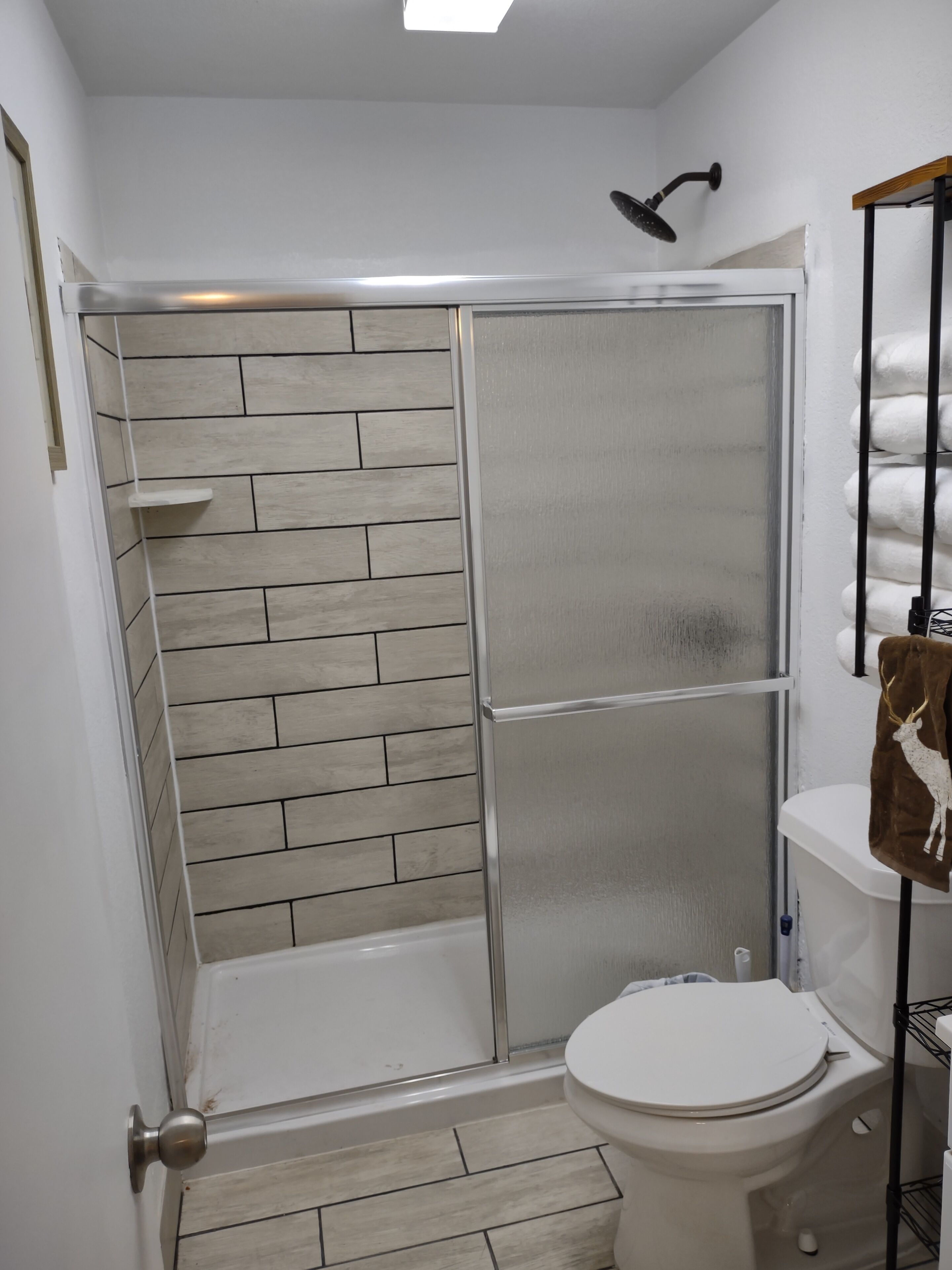Un baño con ducha, inodoro y un perchero con toalla.