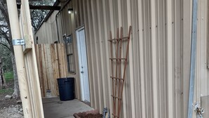 A covered outdoor area with a concrete pathway, wooden fence, and two bags of potting mix. - Horse Ranch House 2 miles to Austin,  Remodeled, Relaxed Atmosphere, SXSW Near (Manchaca)