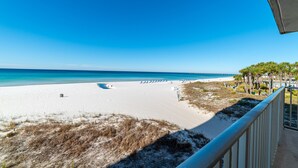 A beach with a clear blue sky, a sandy shore, and a pier extending into the water.