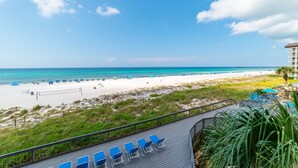 A beach view from a hotel deck with blue lounge chairs and a clear sky. - Beach Days Beachfront-Edgewater Resort in PCB 2nd Floor-3/3-Amazing! (Panama City Beach)