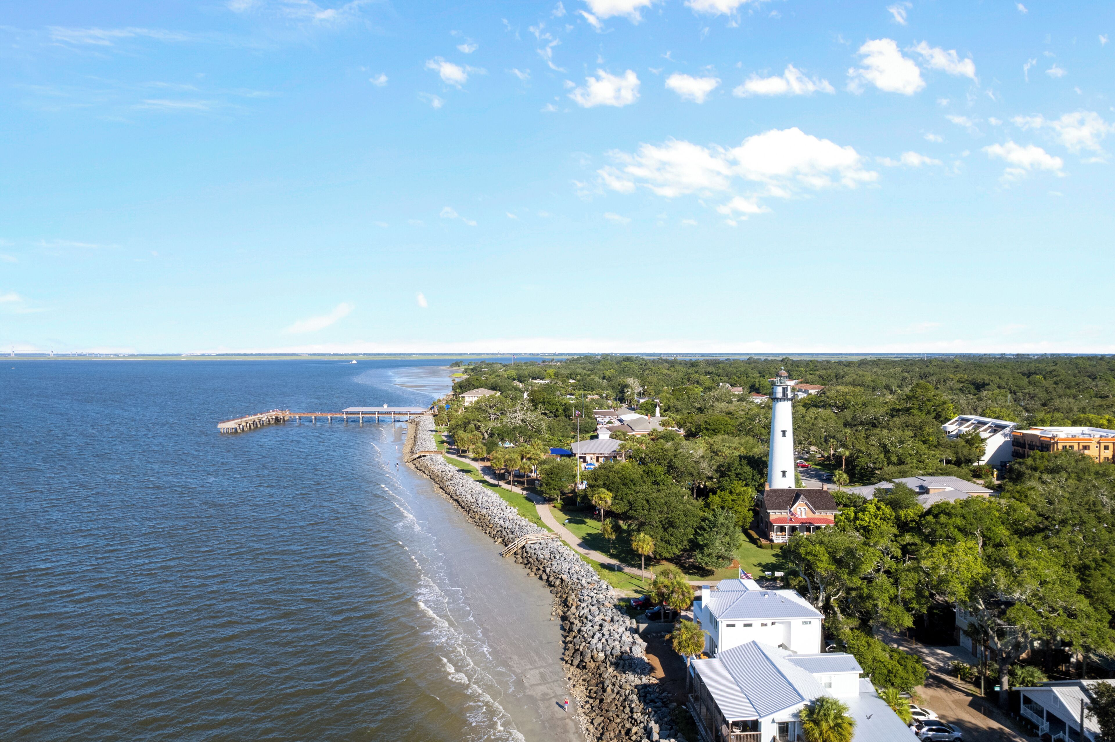 Eine Küstenstadt mit Leuchtturm, Steg und Wohnhäusern entlang der Küste.