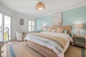 Quarto com uma cama grande, mesa de cabeceira, abajur e vista para o exterior.