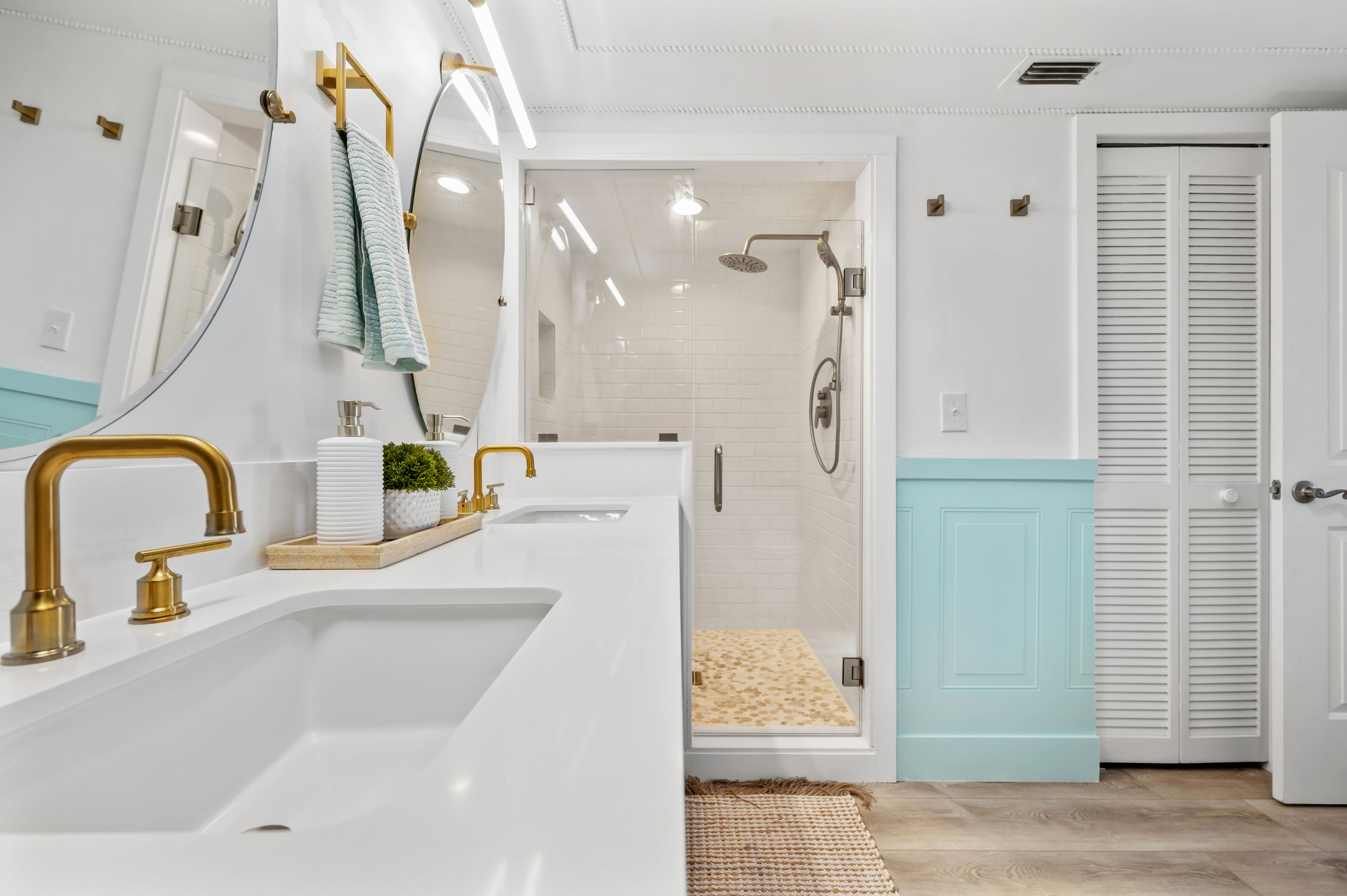 Une salle de bain moderne avec un grand lavabo, des robinets dorés, un miroir et un espace douche.