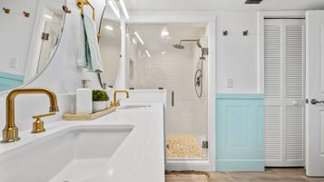 Une salle de bain moderne avec un grand lavabo, des robinets dorés, un miroir et un espace douche.