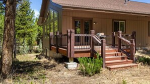 A wooden cabin with a deck, surrounded by trees. - New! Moose Manor | Private Boat Dock (Island Park)