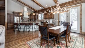 A spacious kitchen with wooden beams, a large island with bar stools, and a chandelier. - New! Moose Manor | Private Boat Dock (Island Park)