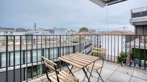 Een balkon met uitzicht op de stad, met een tafel en stoelen.