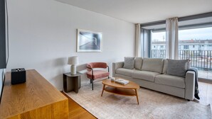 Een moderne woonkamer met een bank, een salontafel, een bijzettafeltje met een lamp, en een lijst met een afbeelding aan de muur.