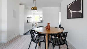 Eine moderne Küche mit weißen Schränken, einem Holzespeisetisch mit schwarzen Stühlen und einer Pendelleuchte.