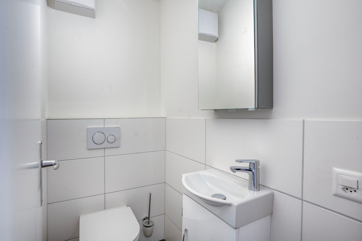 A modern bathroom with a toilet, sink, and mirror.