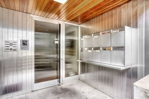 A modern elevator with stainless steel walls and a wooden ceiling. - Hip Gellert 2BR w/ Parking & Shared W/D, 10 min to Market, by Blueground (Basel)