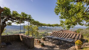 A stone patio with a table and chairs, surrounded by potted plants and a pergola. - Beautiful private villa for 10 guests with private pool, A/C, WIFI, TV and panoramic view (Cortona)