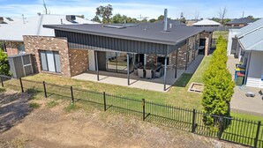 A modern house with a large patio, a fenced yard, and a well-maintained garden.