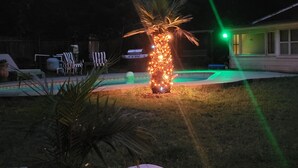 A poolside area with a decorative light structure, lounge chairs, and a grill. - Cozy RV in amazing Austin with AC, WiFi, Swimming Pool (Austin)