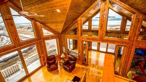 A spacious wooden interior with large windows, a staircase, and leather furniture. - Sunset Kisses. Beachfront Luxury vacation rental (South Haven)