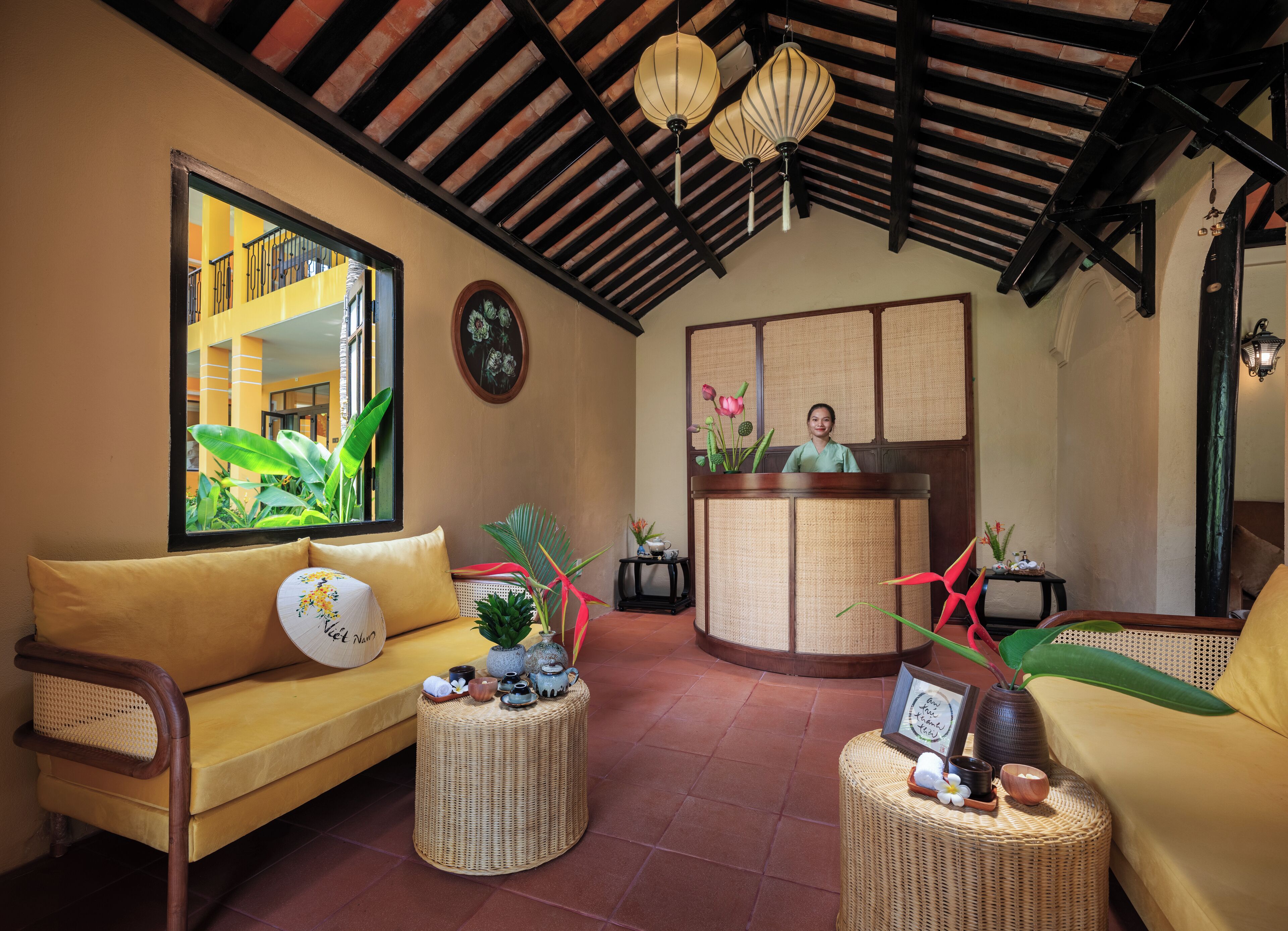 A reception area with a receptionist desk, a sofa, and a wicker coffee table with decorative items.