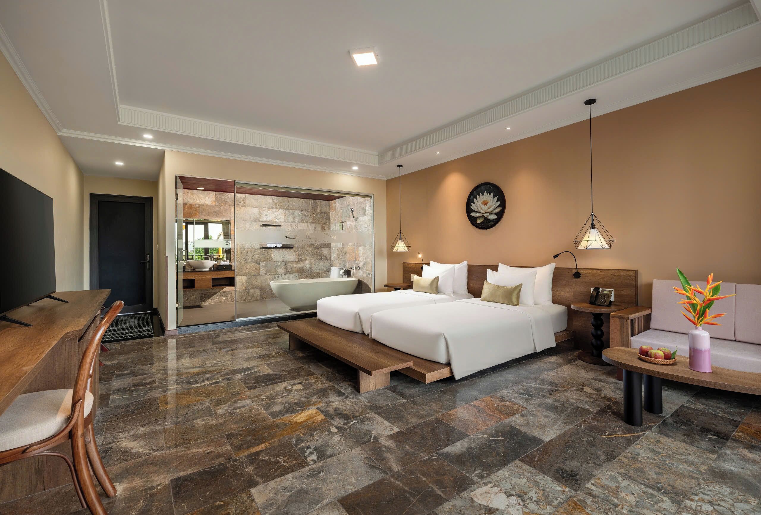 Quarto de hotel moderno com uma cama grande, uma escrivaninha, um sofá, banheiro com banheira e uma parede de pedra.