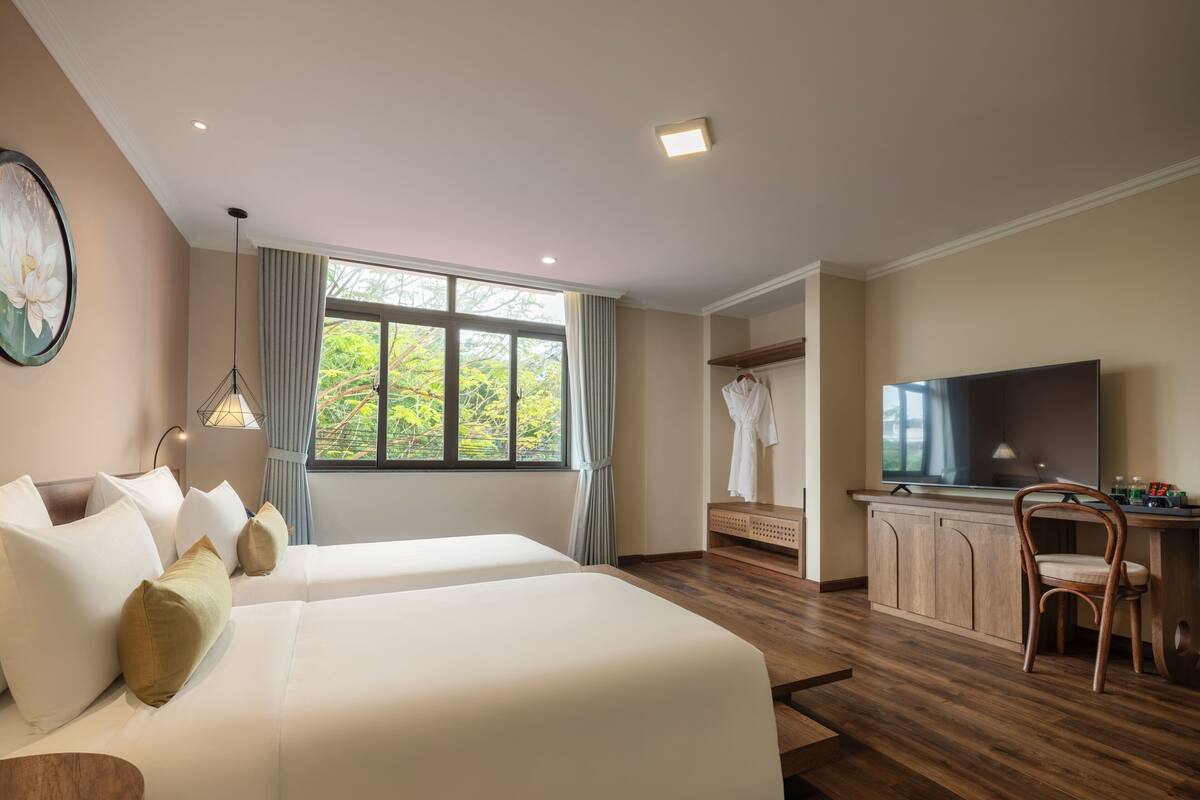 A hotel room with two beds, a TV, a desk, and a chair.