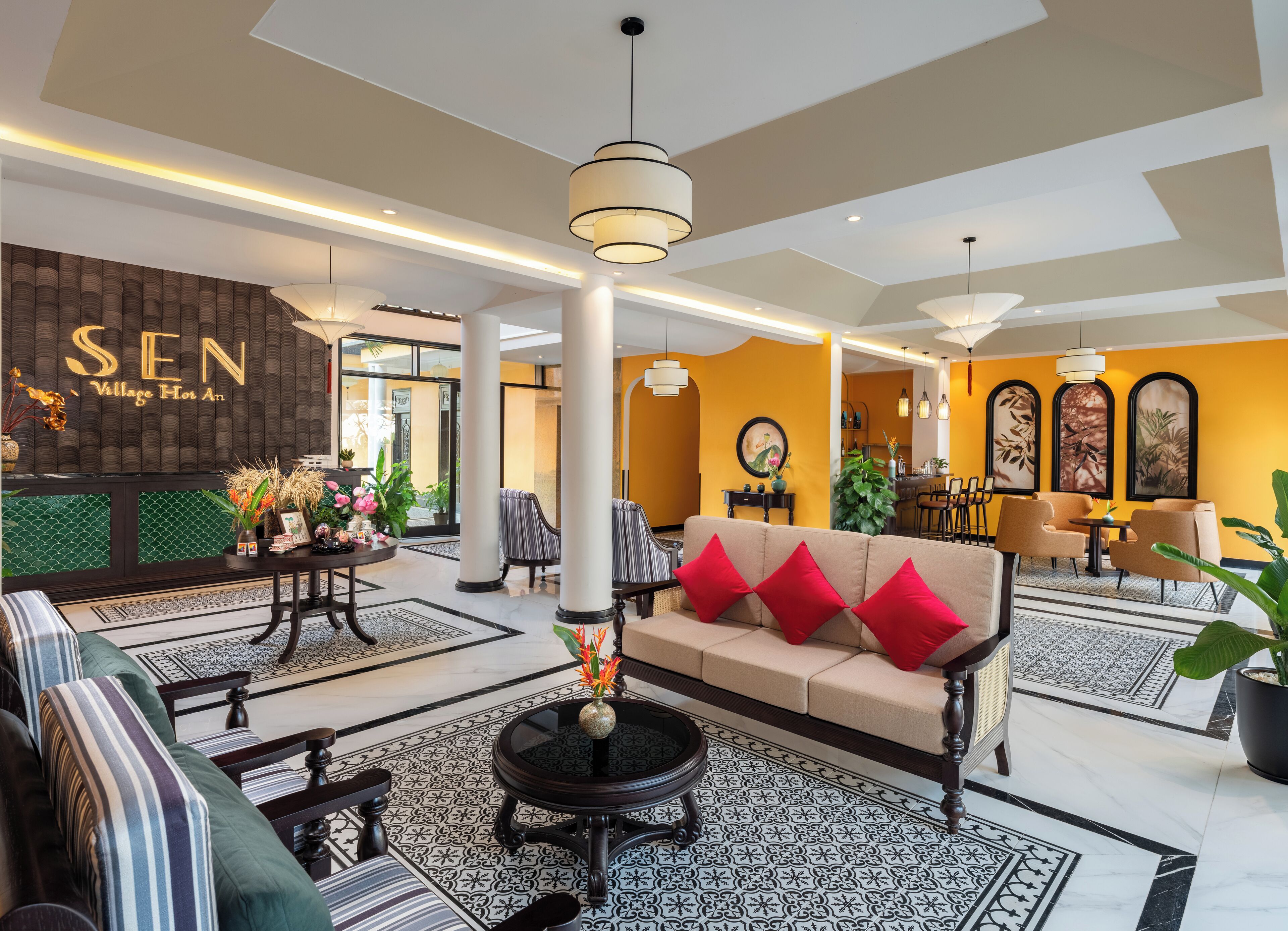 A hotel lobby with a sofa, chairs, a round table, and a reception desk.