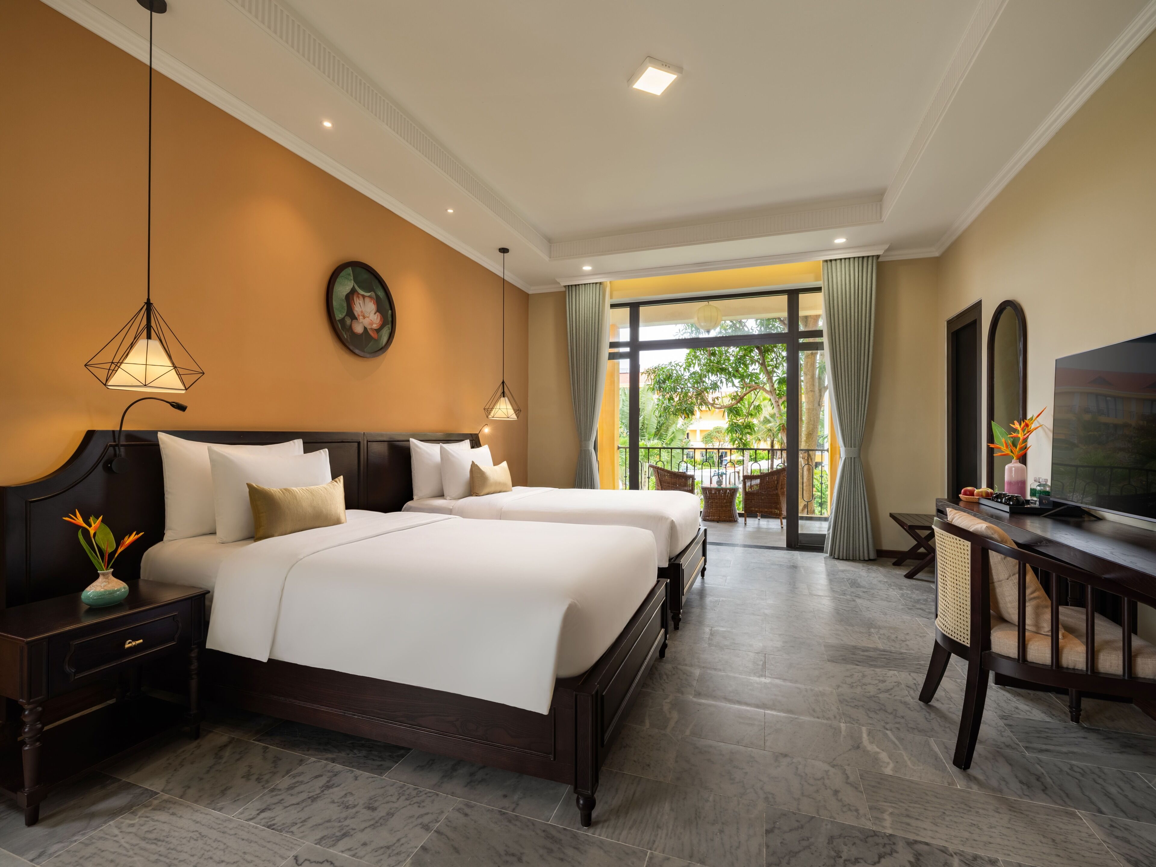 A hotel room with two beds, a TV, a desk, and a balcony with a view.