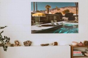 Zona piscina con lettini e ombrellone, circondata da rocce e libri.