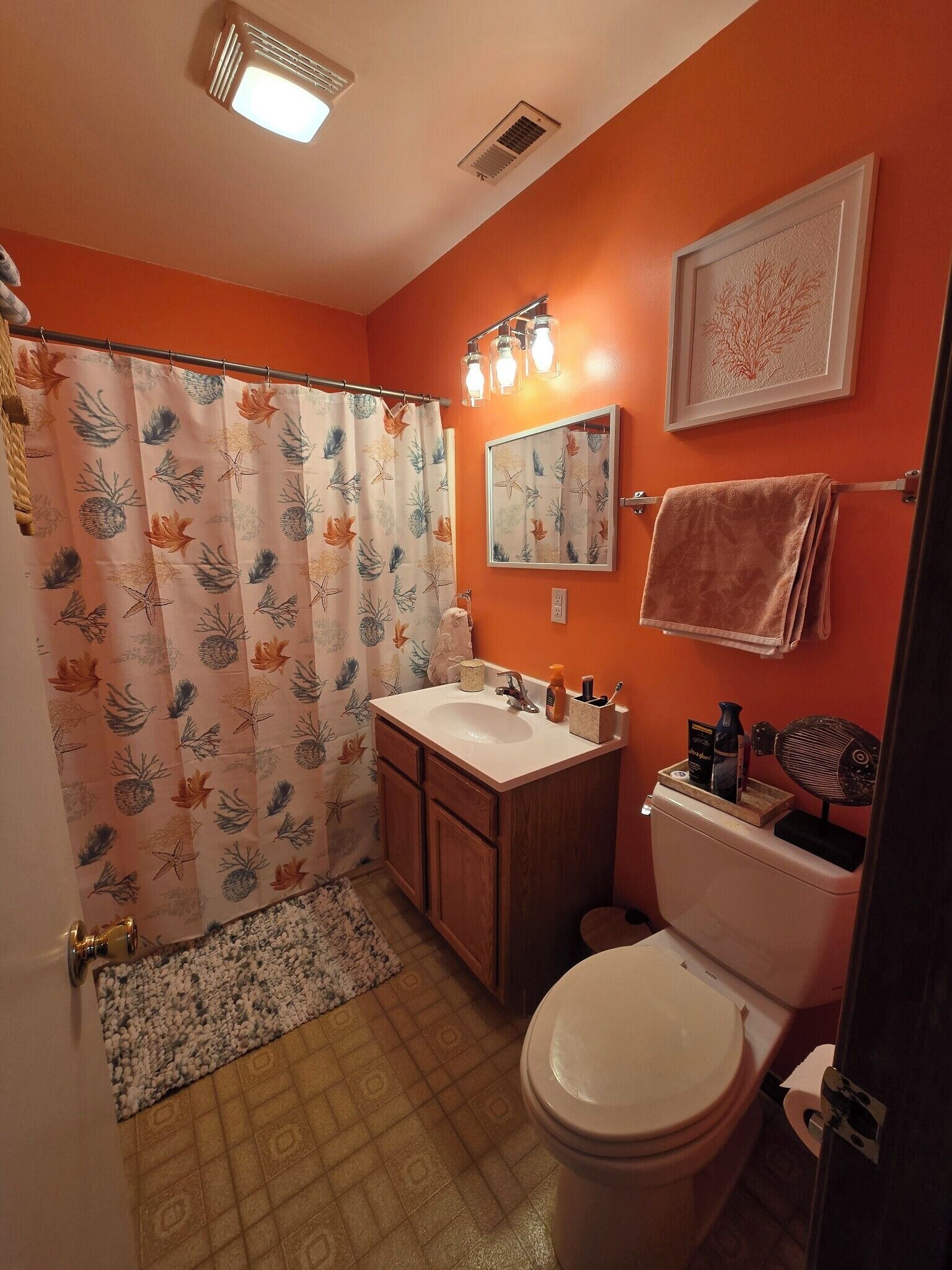 Une salle de bain équipée d’un rideau de douche, d’un lavabo, d’un miroir, d’un porte-serviettes et de toilettes.