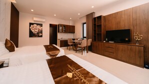 Una habitación de hotel moderna con dos camas, zona de comedor, cocina y televisor.