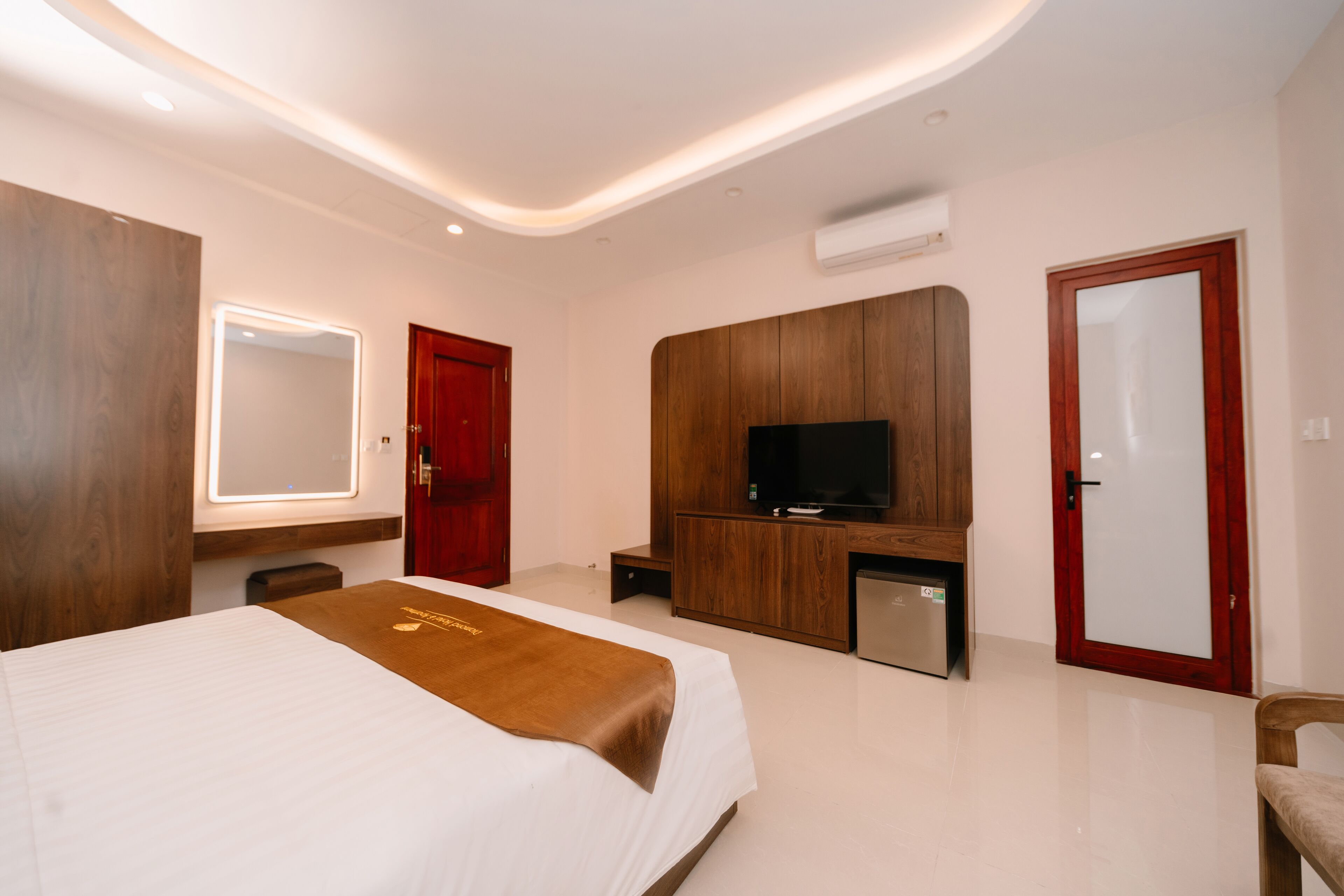 Una habitación de hotel moderna con una cama grande, televisión, escritorio y espejo.