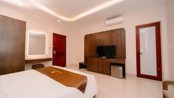 Una habitación de hotel moderna con una cama grande, televisión, escritorio y espejo.