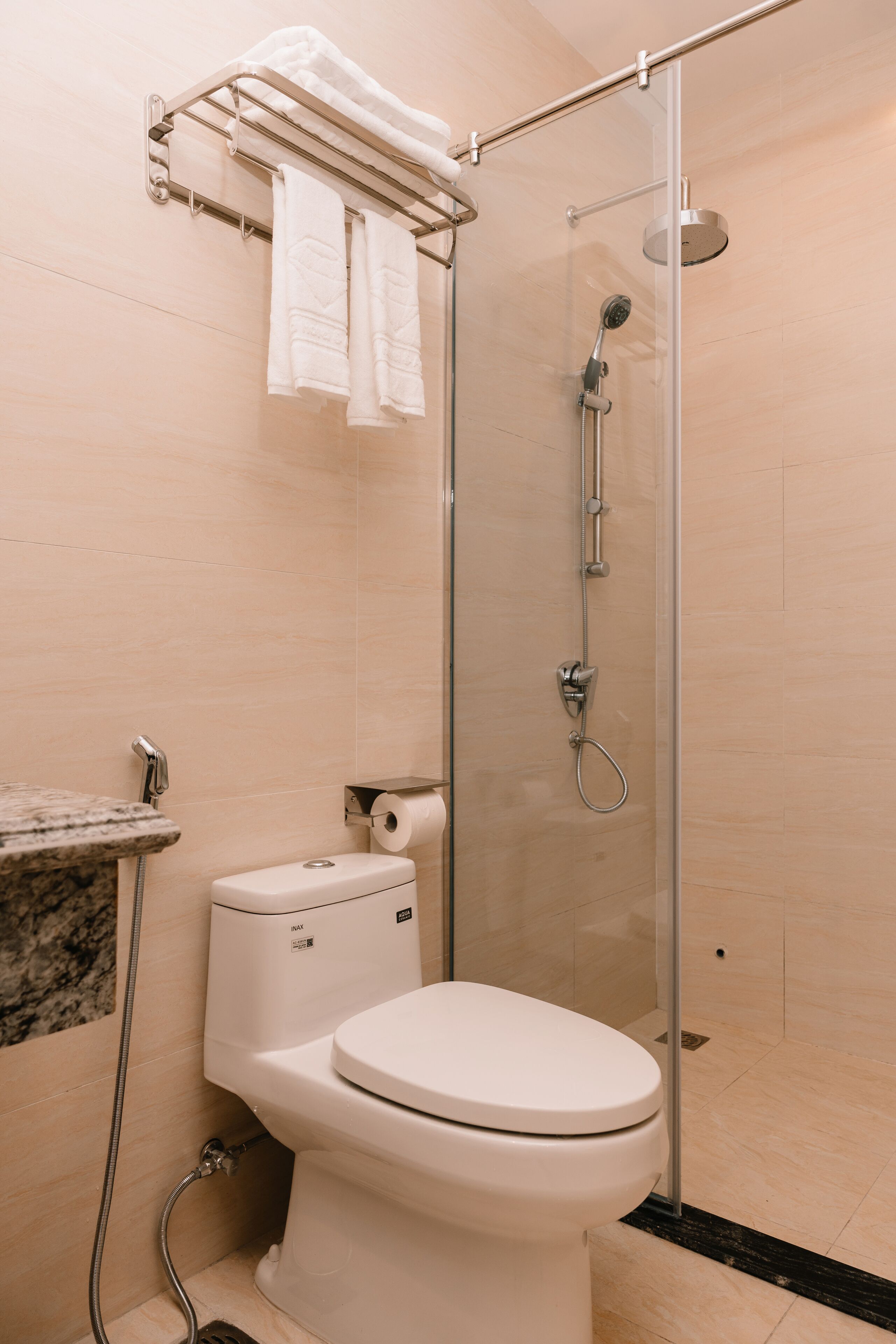 Une salle de bain moderne équipée de toilettes, d’une douche à parois de verre et d’un porte-serviettes avec deux serviettes.