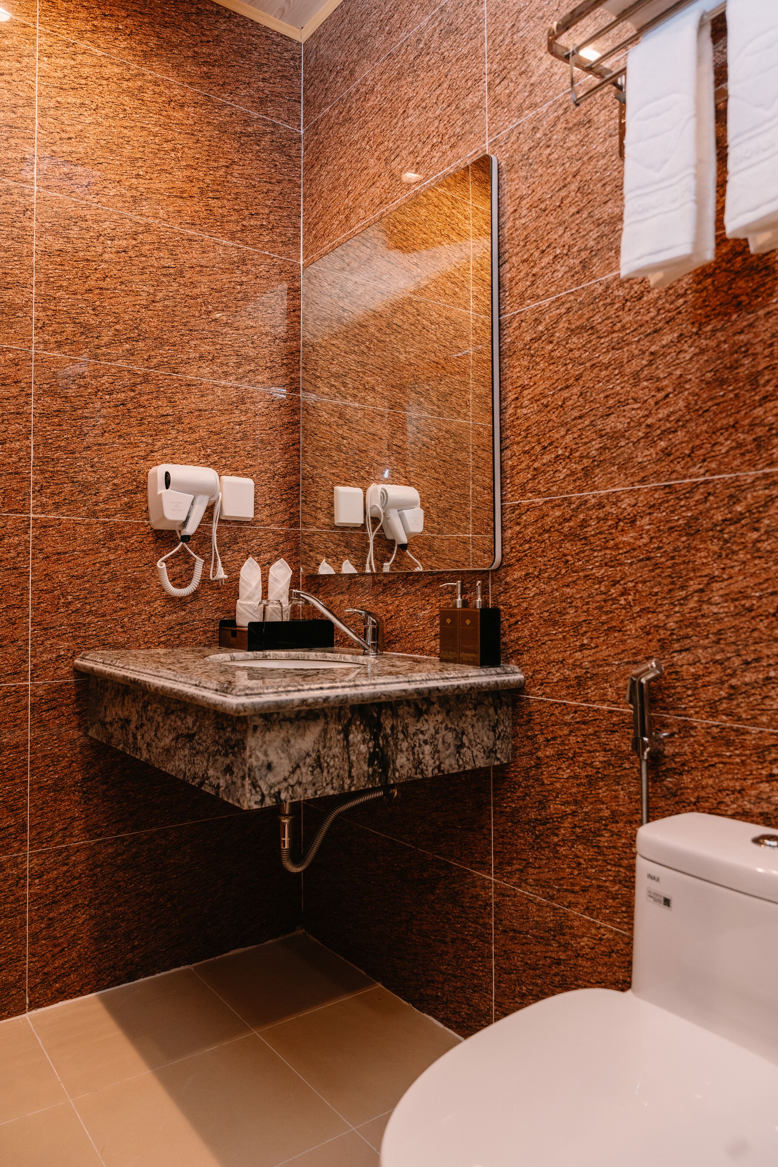 A modern bathroom with a granite countertop sink, a mirror, and a toilet.