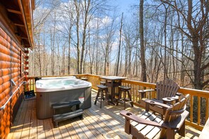 Una terraza de madera con un jacuzzi, sillas de madera y una mesa.