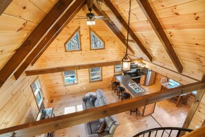 Una cabaña de madera con habitación en el altillo, cocina y comedor.
