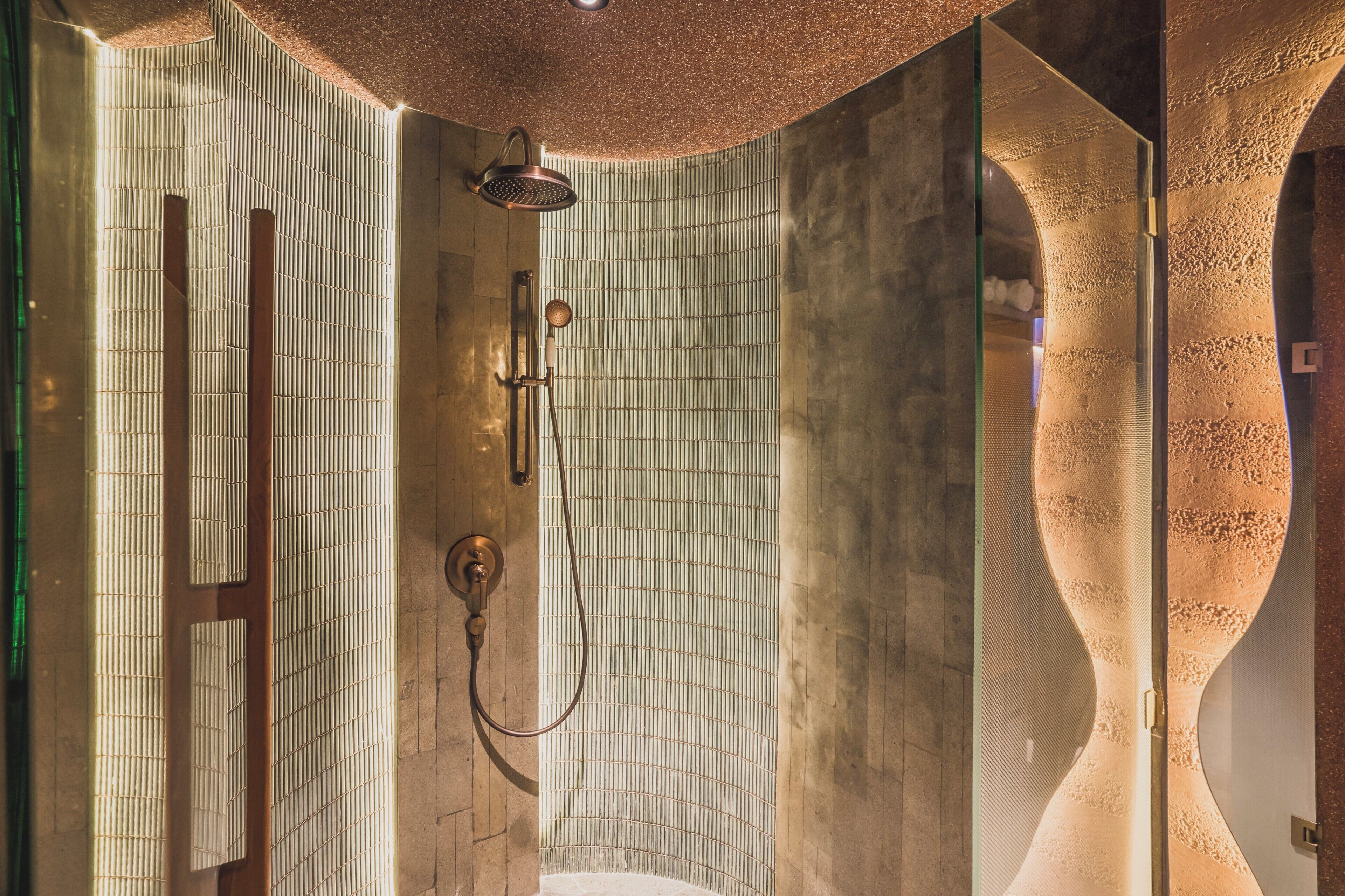 Un baño moderno con ducha, puerta de vidrio y un diseño de pared curvo original.