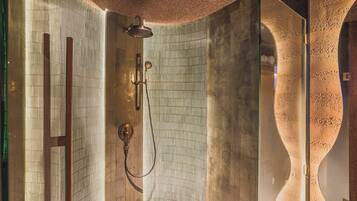 Un baño moderno con ducha, puerta de vidrio y un diseño de pared curvo original.