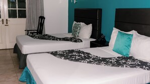 Une chambre d’hôtel avec deux lits, une porte dotée d’une fenêtre et un mur d’accent de couleur turquoise.