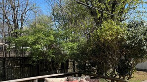 Eine Terrasse im Freien mit Korbmöbeln, einem runden Holztisch und einer blau-weißen Decke.