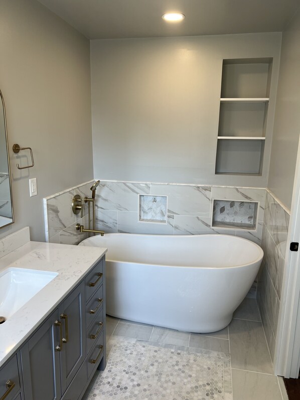 A modern bathroom with a freestanding bathtub, a vanity with a sink, and a shower area.