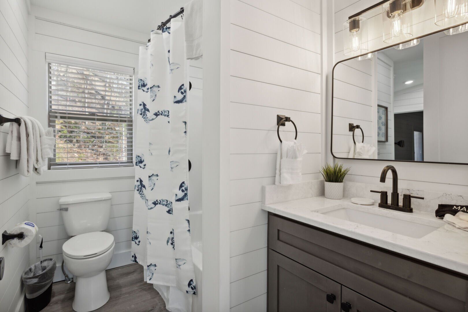 Un baño con inodoro, lavabo con espejo y cortina de ducha.