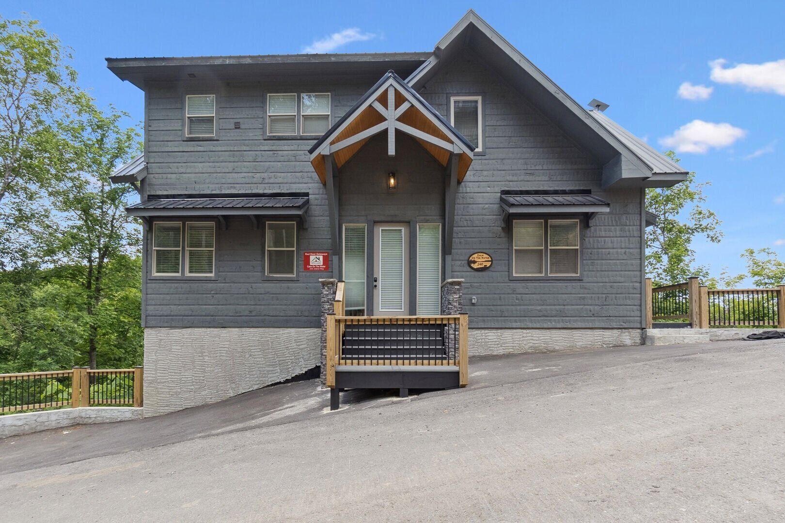 A two-story building with a grey exterior, a wooden front porch, and a sign indicating a lodge.